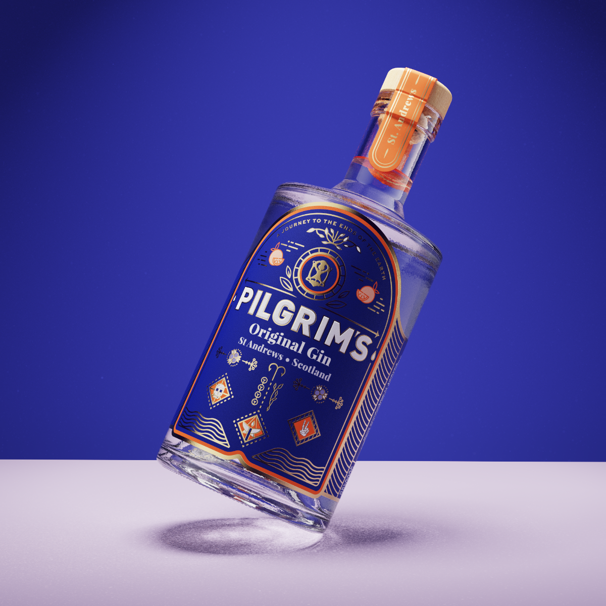 A bottle of Pilgrims Original Gin leaning on its side against a blue studio background, with a white surface beneath it and a visible brand label.